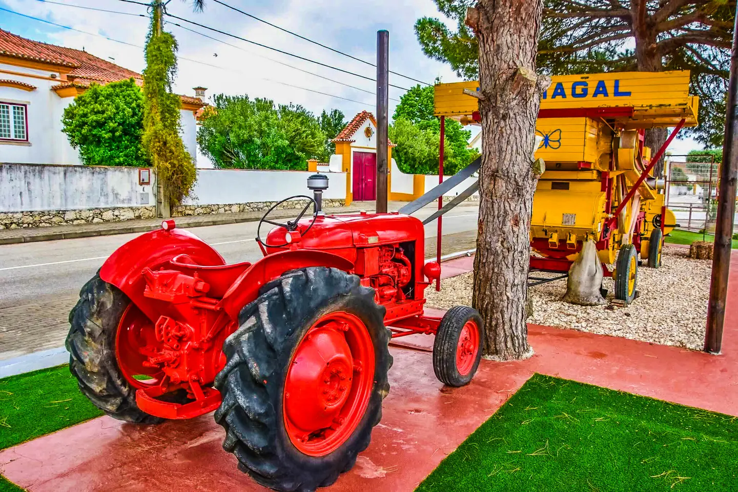 Trator vermelho e antiga máquina agrícola no jardim